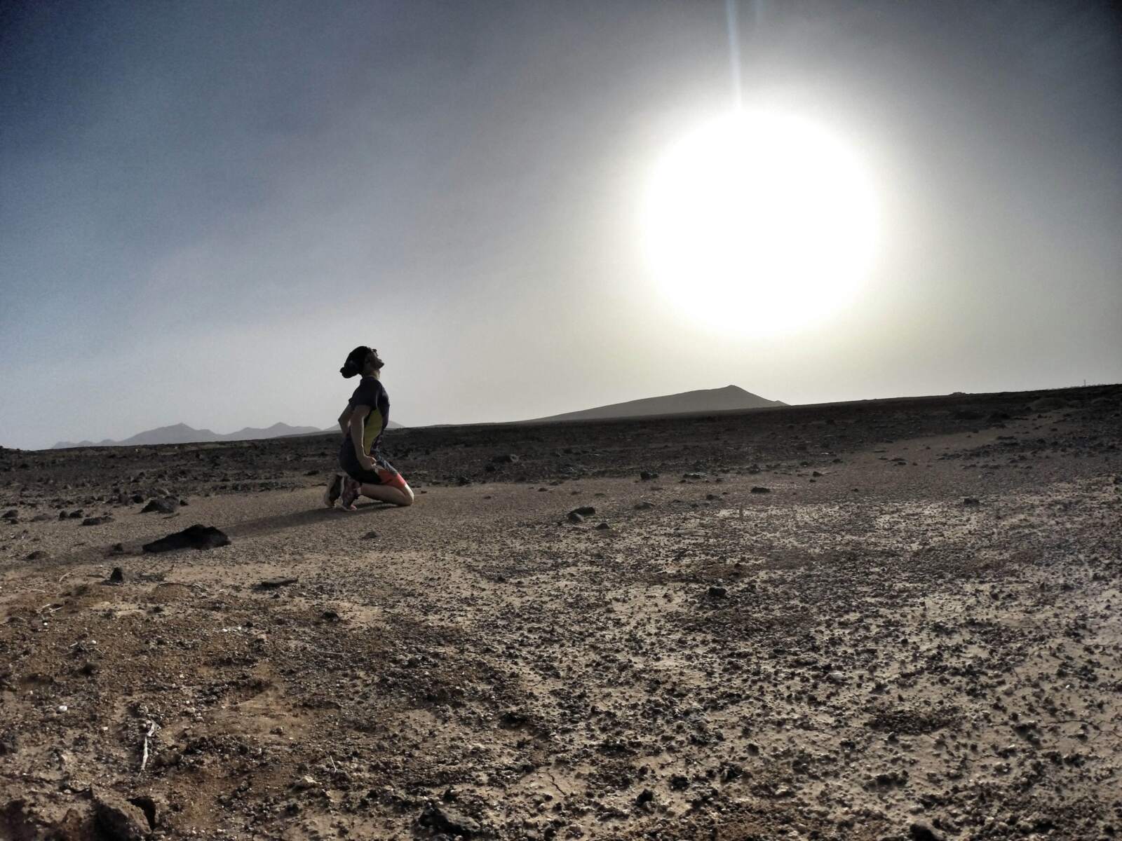 Víctor arrodillado en el desierto volcánico de Lanzarote, a contraluz